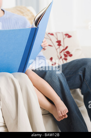 Parents reading to daughter on sofa Stock Photo