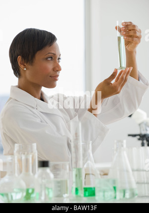African scientist looking at vial of liquid Stock Photo