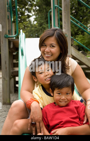 Asian family sitting together on slide Stock Photo