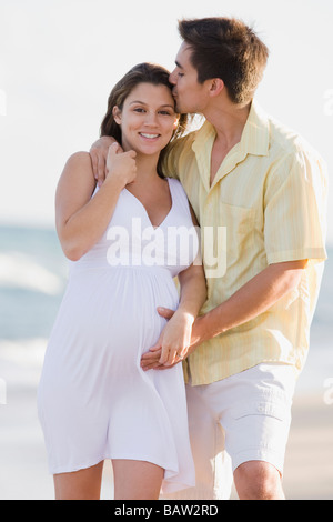 Husband hugging pregnant wife on beach Stock Photo