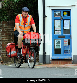 Postman cycling on his Royal Mail route wearing protective headgear Stock Photo