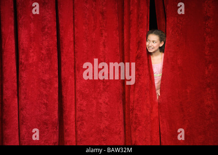 Mixed race person hiding behind stage curtain Stock Photo