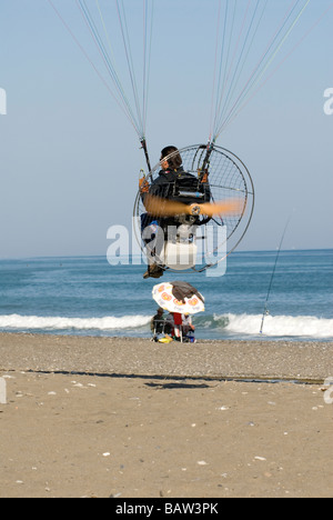 Motor powered Para glider flying low over beach Stock Photo