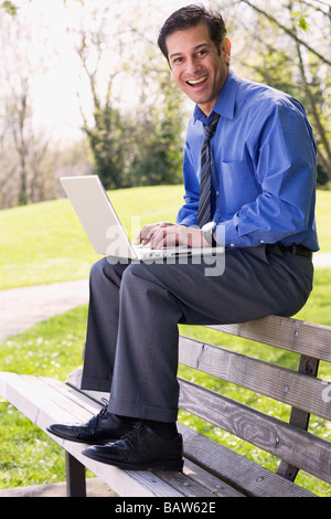 Hispanic businessman using laptop outdoors Stock Photo