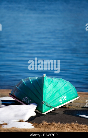 Upturned moored fiberglass green rowboat ( skiff / dinghy ) Stock Photo