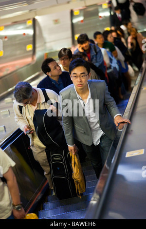 Young Asian Man Walking on an Escalator in Hong Kong Stock Photo