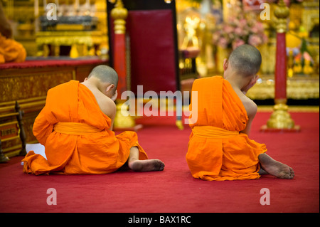 Two young Monks sleeping though afternoon prayer. Wat Pho, Bangkok, Thailand Stock Photo