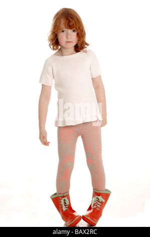 A girl in red rubber boots and a yellow raincoat runs through puddles ...