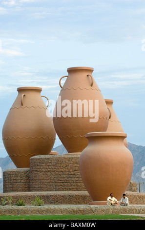 Two men sitting in front of giant clay jugs, Roundabout, Dibba, Oman Stock Photo