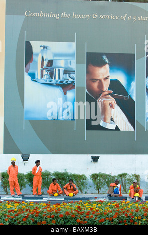 Construction workers having a break beneath an advertisement for luxury, Dubai, United Arab Emirates Stock Photo