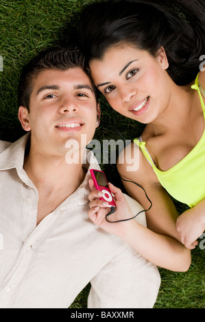 Young couple listening music on a mp3 player while relaxing outdoor Stock Photo