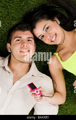 Young couple listening music on a mp3 player while relaxing outdoor Stock Photo