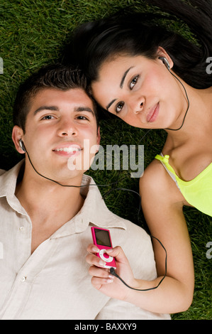 Young couple listening music on a mp3 player while relaxing outdoor Stock Photo