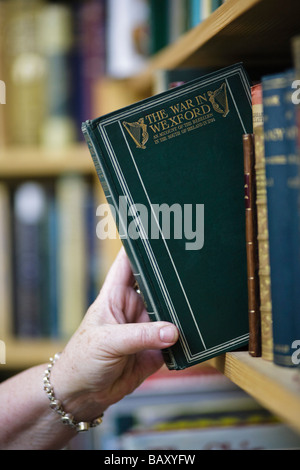 Hand on a leather bound book in an antiquarian booksellers, UK Stock Photo
