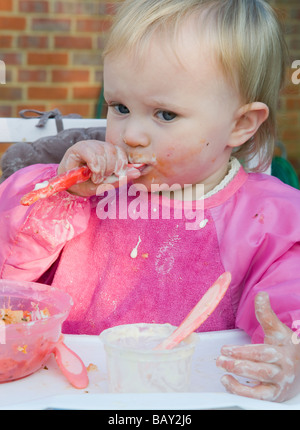 Toddler, 16months old,  girl , feeding herself and causing a mess Stock Photo