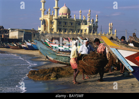 Fishermen and boats on the beach in front of mosque, Kovalam, Kerala, India Stock Photo