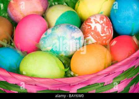 A close up of group of colored Easter eggs in a basket of grass Stock Photo