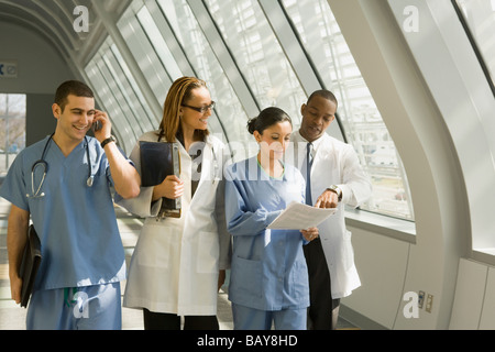 Multi-ethnic doctors and nurses reviewing paperwork in corridor Stock Photo