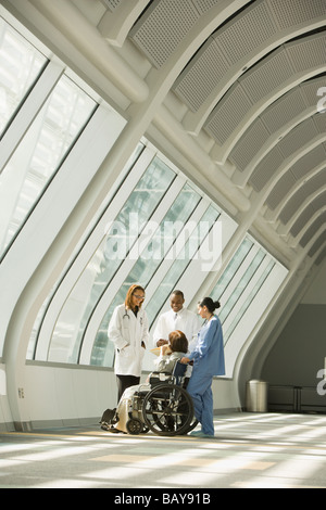 Multi-ethnic doctors and nurse with patient in wheelchair Stock Photo