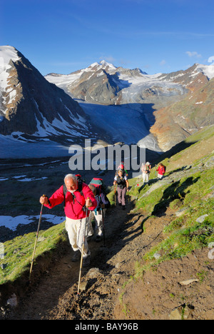 group of hikers ascending Pitztaler Joechl with linker Fernerkogel, Wildspitze and Hinterer Brunnenkogel above hut Braunschweige Stock Photo