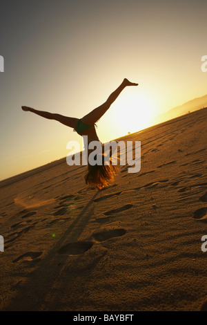 Mixed race woman doing cartwheel on beach Stock Photo