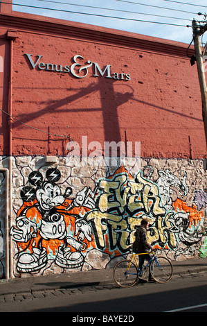 Graffiti Venus and Mars and a man with a bicycle on Brunswick Street Fitzroy Melbourne Victoria Australia Stock Photo