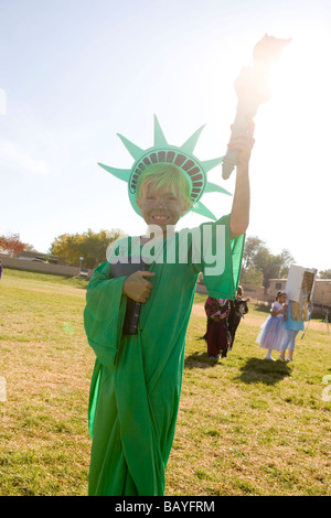 elementary school age girl dressed up in Statue of Liberty halloween costume, holding torch to sunlight Stock Photo
