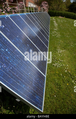 sun shining down on an array of blue tinted polycrystalline silicon photovoltaic solar panels in county tyrone northern ireland Stock Photo