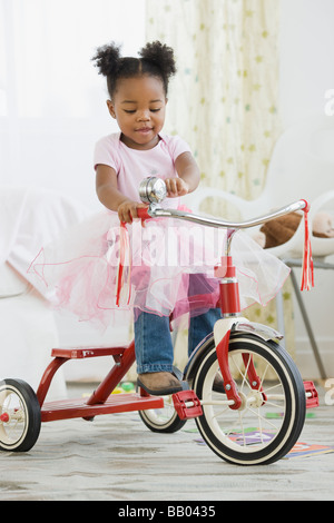 African American girl in costume riding tricycle Stock Photo