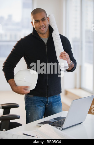 African American architect holding hard hat and blueprints Stock Photo