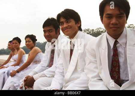 A wedding party sits by while the bride and groom are photographed at Angkor Wat, Siem Reap Province, Kingdom of Cambodia. Stock Photo