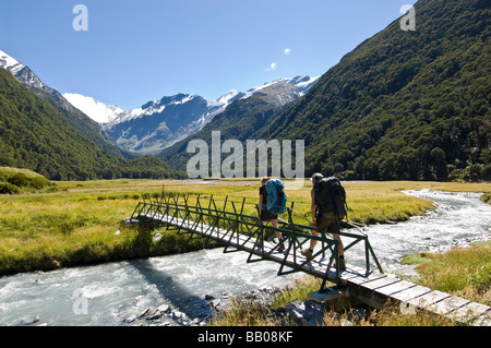 Hikers crossing bridge in West Matukituki River valley Mount Aspiring National Park South Island New Zealand Stock Photo