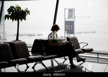 A woman sitting in the departures lounge of Beijing Capital Airport terminal three China Stock Photo