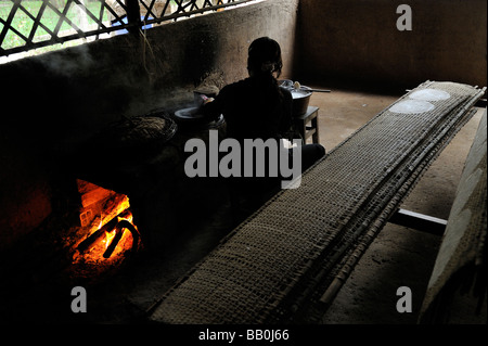 Woman preparing rice paper in traditional method, cooking on a wood-fired stove. Cu Chi Tunnel Memorial, Vietnam Stock Photo