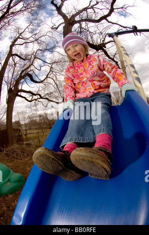 A child laughs as she goes down a slide on a crisp day. Stock Photo