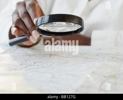 African woman using magnifying glass on map Stock Photo