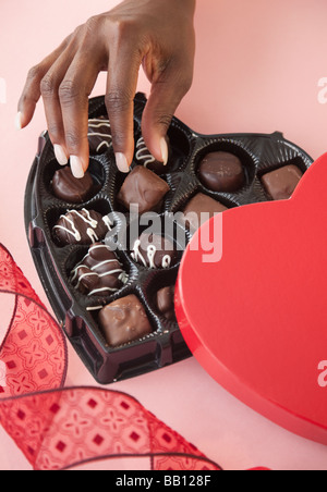 African woman taking chocolates from Valentines box Stock Photo