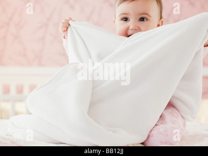 Mixed race baby girl playing with blanket Stock Photo