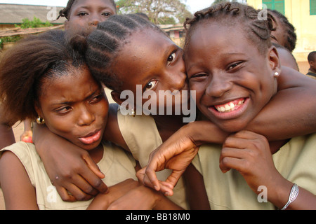 Benin Porto Novo Portrait of girlfriends hugging one kissing the other Stock Photo