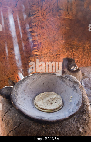 Sunlight and smoke with Corn tortillas cooking in metal wok pan greased with bone marrow in native Mayo village, Capomos, Mexico Stock Photo