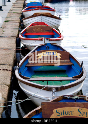 Wooden rowing boats, used for hire by day trippers, lined up in a row along Bude Canal Stock Photo