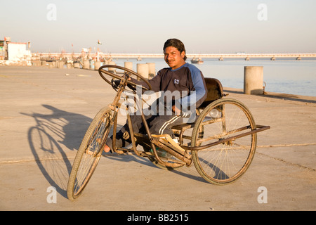A young disabled man sits in his tricycle in the former Portuguese colony of Diu, India. Stock Photo