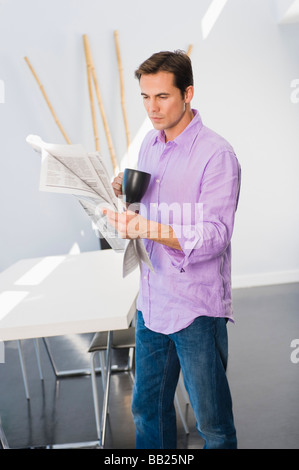 Man reading a newspaper and drinking a cup of coffee Stock Photo