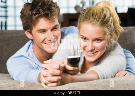 Couple holding a remote control and smiling Stock Photo