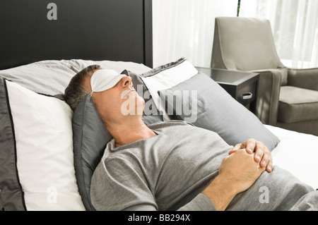 Man sleeping in bed wearing an eye mask Stock Photo