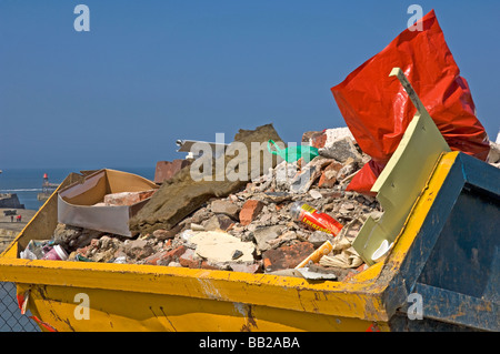 A yellow metal skip filled with builders rubble England UK United Kingdom GB Great Britain Stock Photo