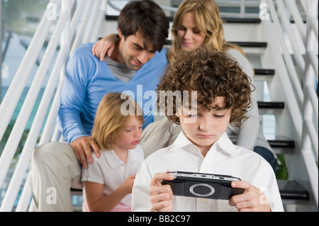 Parents sitting on steps with their children playing video games