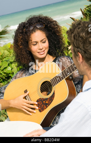 Woman playing a guitar in front of a man Stock Photo