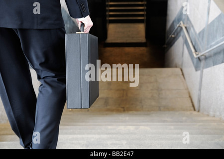 Businessman Carrying a Briefcase Going Down Stairs to a Subway Station Rear View Stock Photo