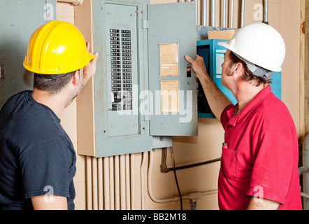 Electricians examining a circuit breaker panel in an industrial setting  Stock Photo
